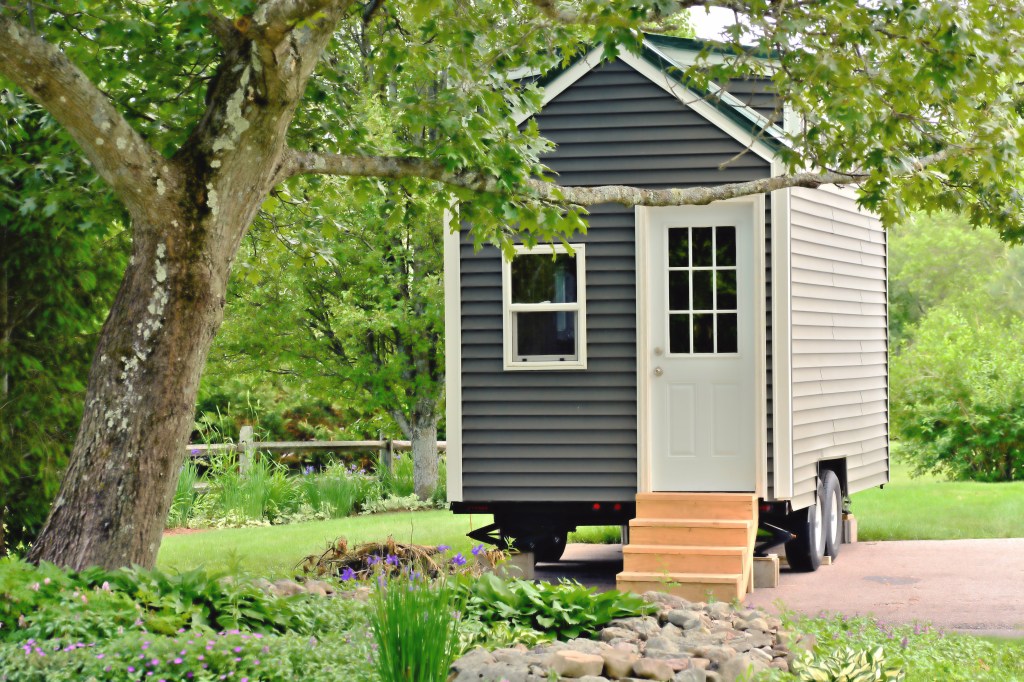 A small gray mobile home on a trailer